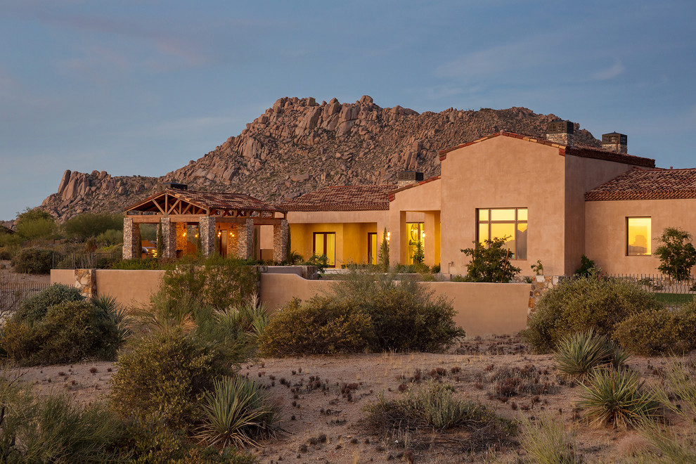 Example of a huge tuscan brown one-story stucco house exterior design in Phoenix with a tile roof