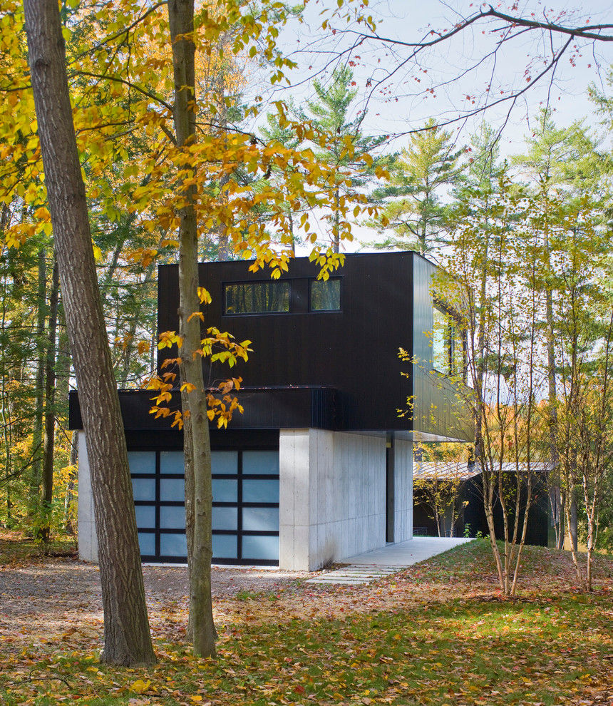 На фото: большой, двухэтажный, черный частный загородный дом в современном стиле с облицовкой из металла, плоской крышей и металлической крышей