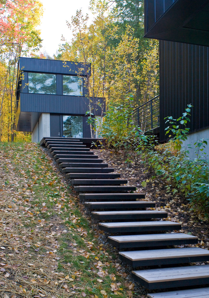 Imagen de fachada de casa negra actual grande de dos plantas con revestimiento de metal, tejado plano, tejado de metal y escaleras