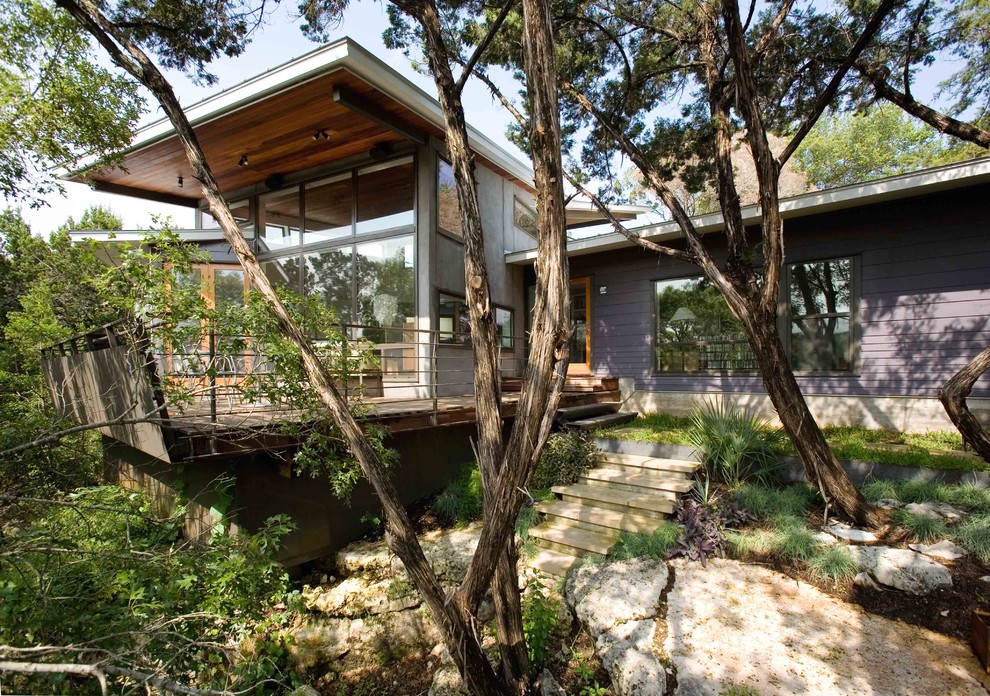 На фото: большой, двухэтажный, серый частный загородный дом в современном стиле с облицовкой из камня и плоской крышей с