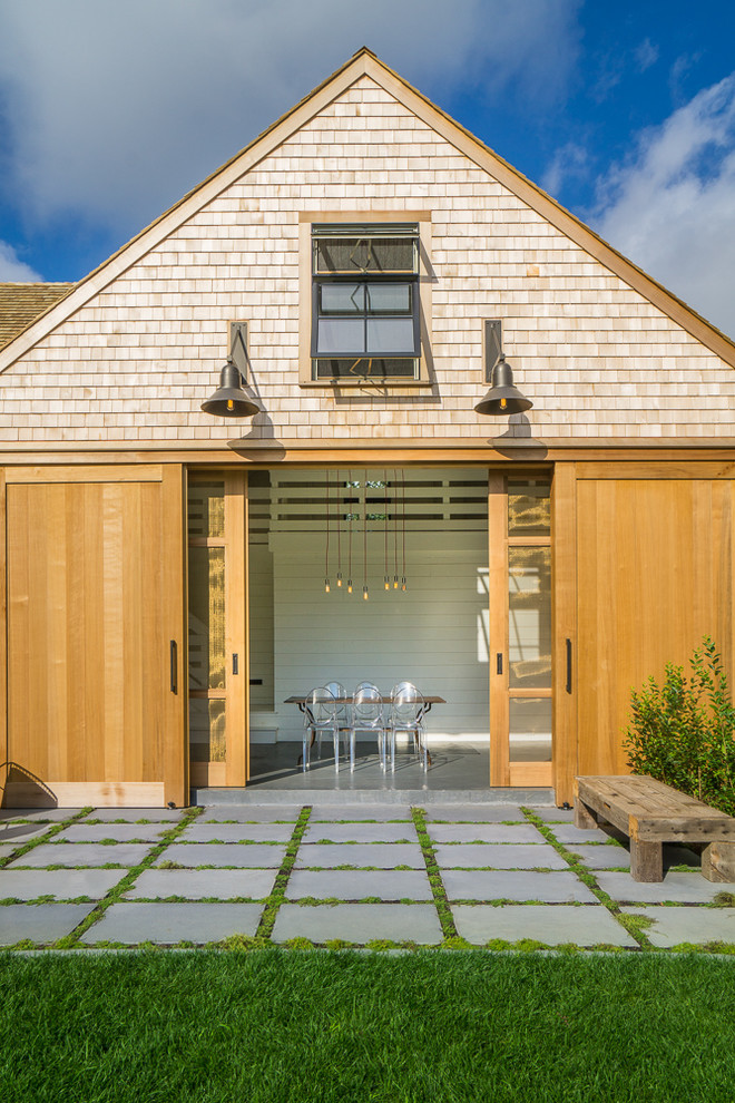 This is an example of a large and beige rural two floor house exterior in Boston with wood cladding and a pitched roof.