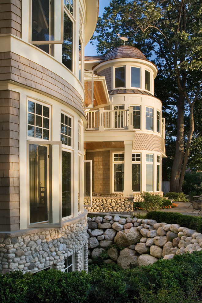 Cette photo montre une très grande façade de maison beige chic en pierre à deux étages et plus avec un toit à quatre pans.