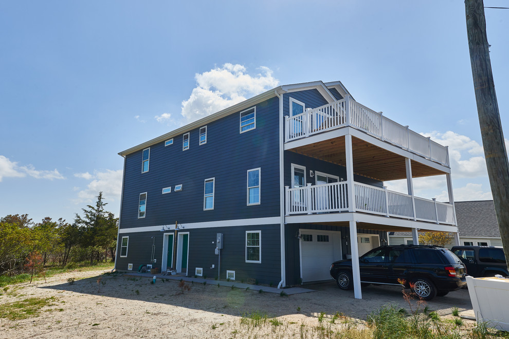 Cette image montre une grande façade de maison bleue marine à deux étages et plus avec un revêtement en vinyle, un toit à deux pans et un toit en shingle.