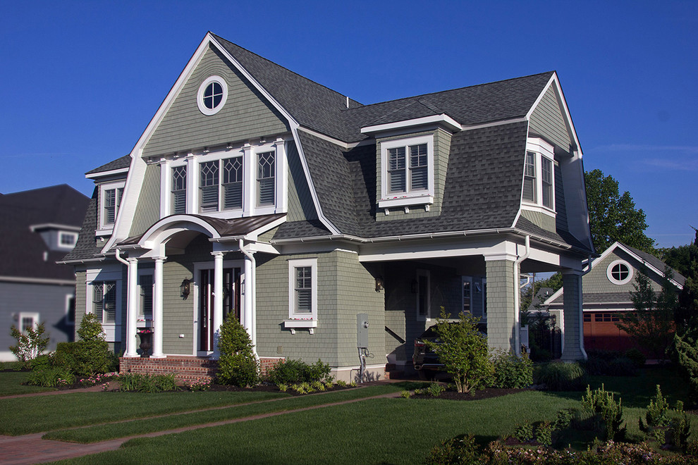 Cette photo montre une façade de maison verte chic de taille moyenne et à un étage avec un revêtement en vinyle, un toit de Gambrel et un toit en shingle.