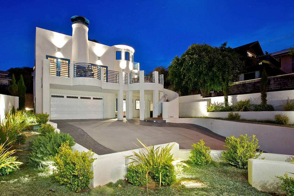 Cette photo montre une grande façade de maison blanche moderne en stuc à un étage avec un toit plat.