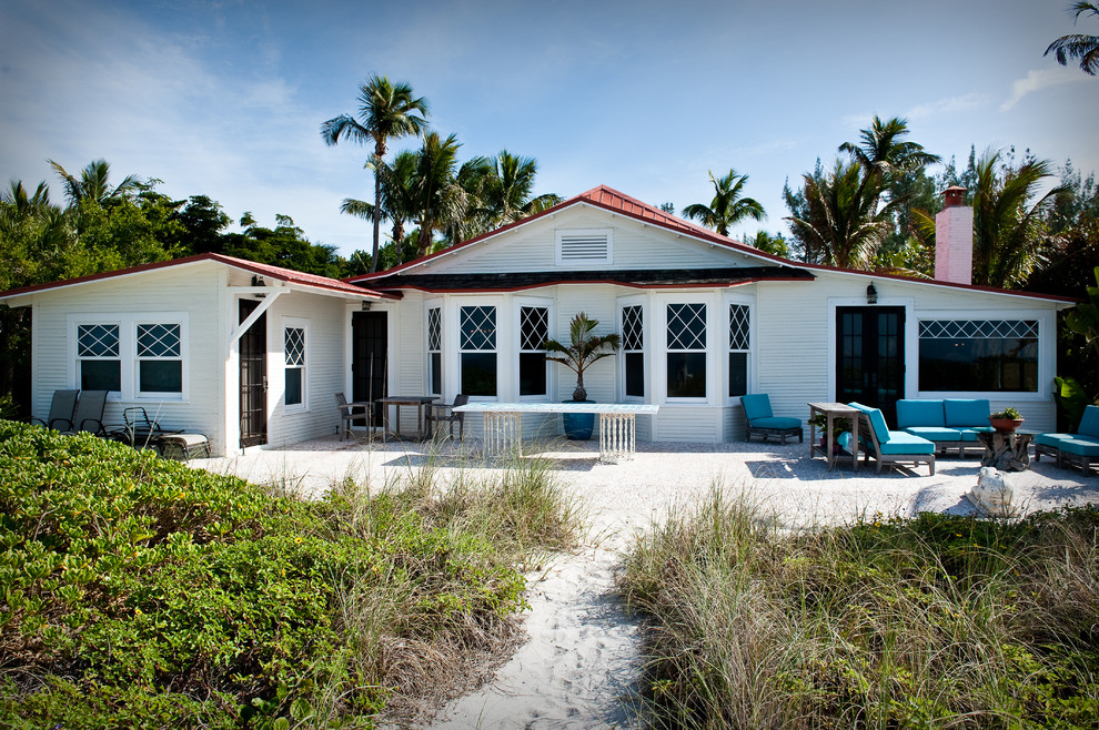Immagine della villa piccola bianca tropicale a un piano con rivestimento in legno, tetto a padiglione e copertura in metallo o lamiera