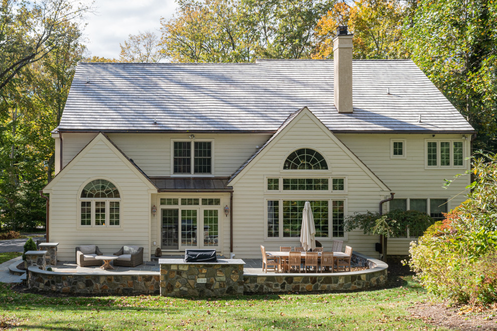 Imagen de fachada de casa blanca clásica grande de dos plantas con tejado a dos aguas y tejado de teja de madera