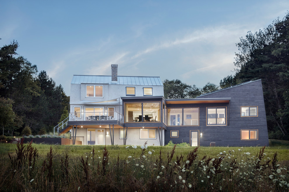 Diseño de fachada de casa gris actual de dos plantas con tejado de un solo tendido, revestimiento de madera y tejado de metal
