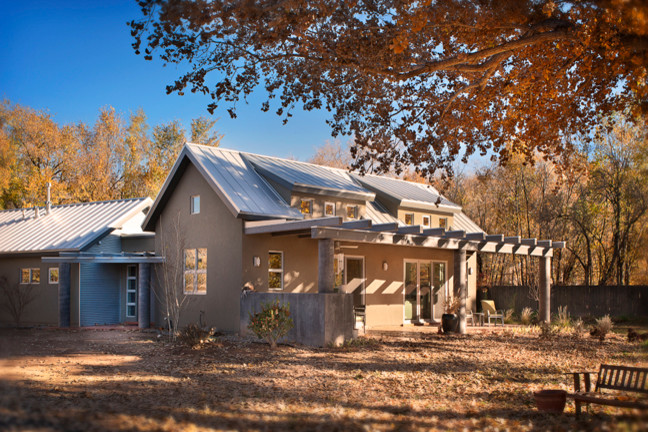 Diseño de fachada de casa beige de estilo de casa de campo de tamaño medio de una planta con revestimiento de estuco, tejado a dos aguas y tejado de metal