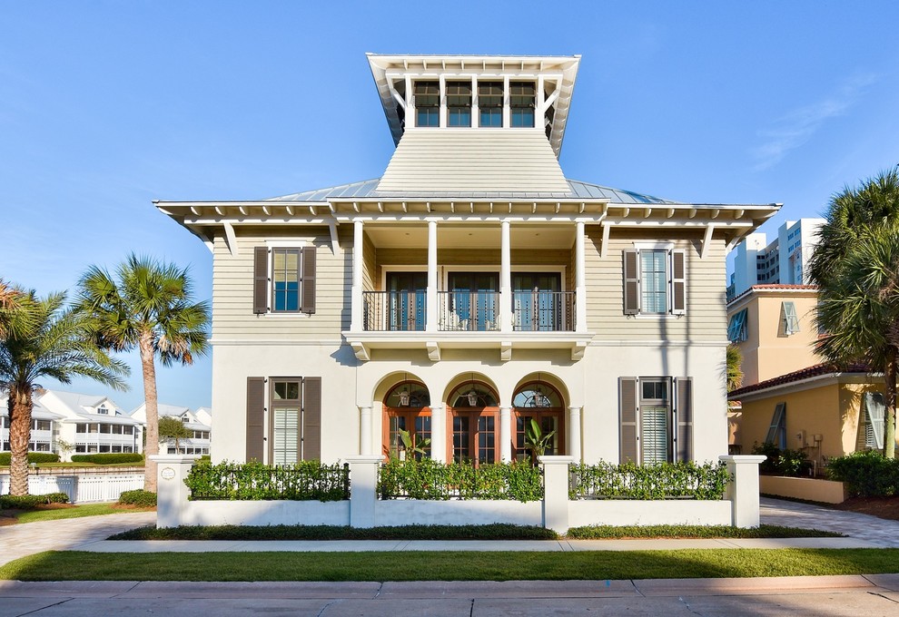 This is an example of a beige beach style house exterior in Jacksonville with three floors and a hip roof.