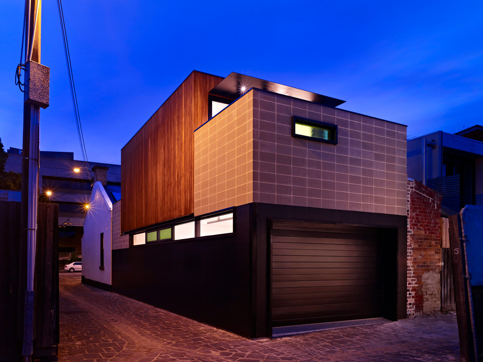 На фото: маленький, двухэтажный, черный дом в стиле модернизм с облицовкой из бетона и двускатной крышей для на участке и в саду с