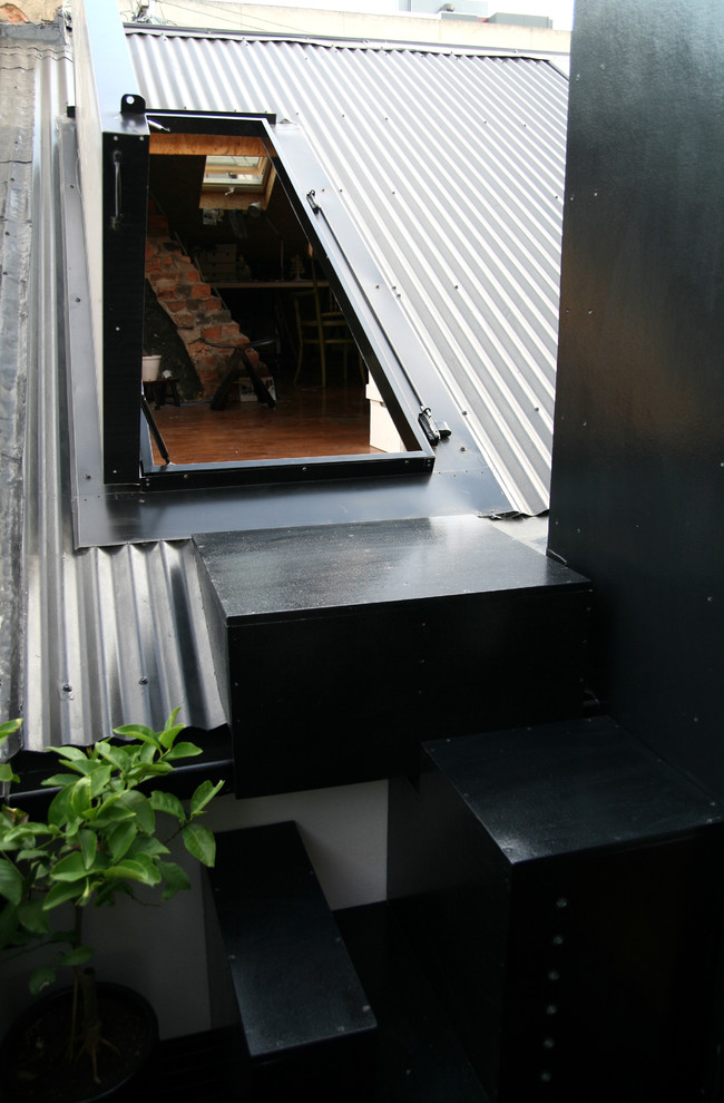 Стильный дизайн: маленький, двухэтажный, черный дом в стиле модернизм с облицовкой из металла и двускатной крышей для на участке и в саду - последний тренд