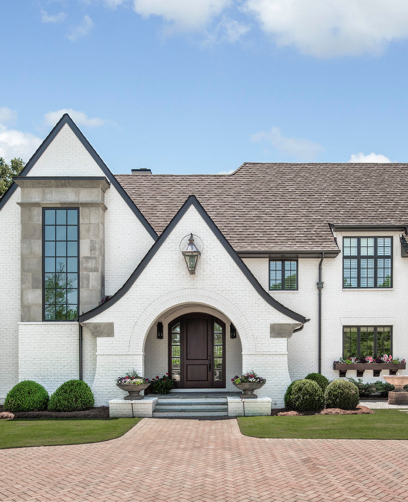 Large country white three-story brick house exterior idea in Charlotte with a shingle roof