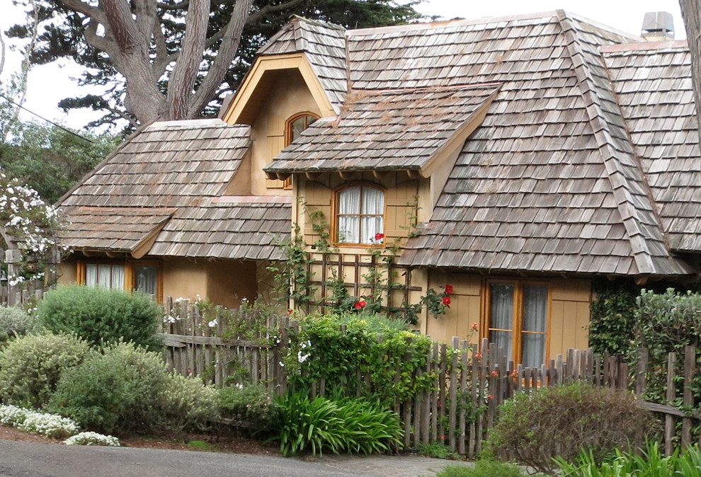Aménagement d'une grande façade de maison beige romantique en bois à un étage avec un toit à deux pans et un toit en tuile.