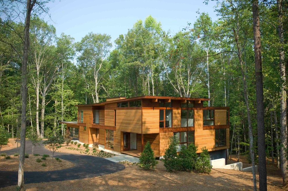 Immagine della villa grande marrone moderna a tre piani con rivestimento in legno e tetto piano