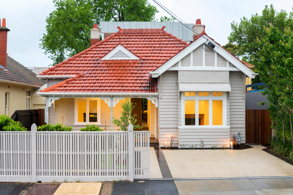 Cette image montre une façade de maison grise bohème de plain-pied avec un toit à deux pans et un toit en tuile.