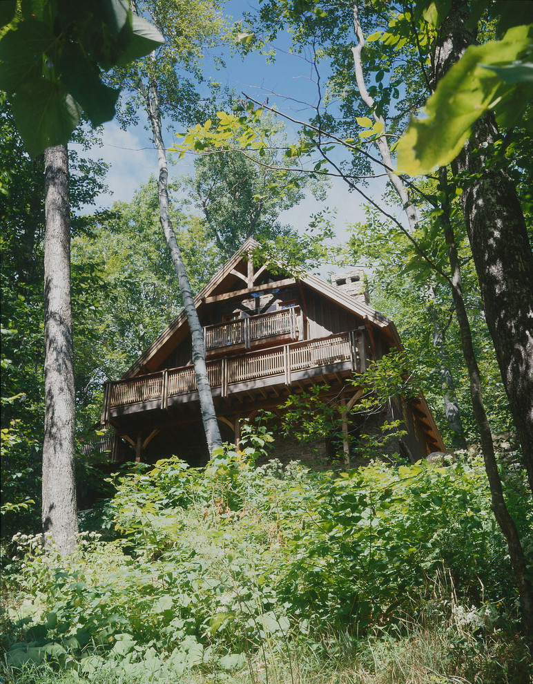Esempio della facciata di una casa marrone classica a tre piani con tetto a capanna e rivestimento in legno