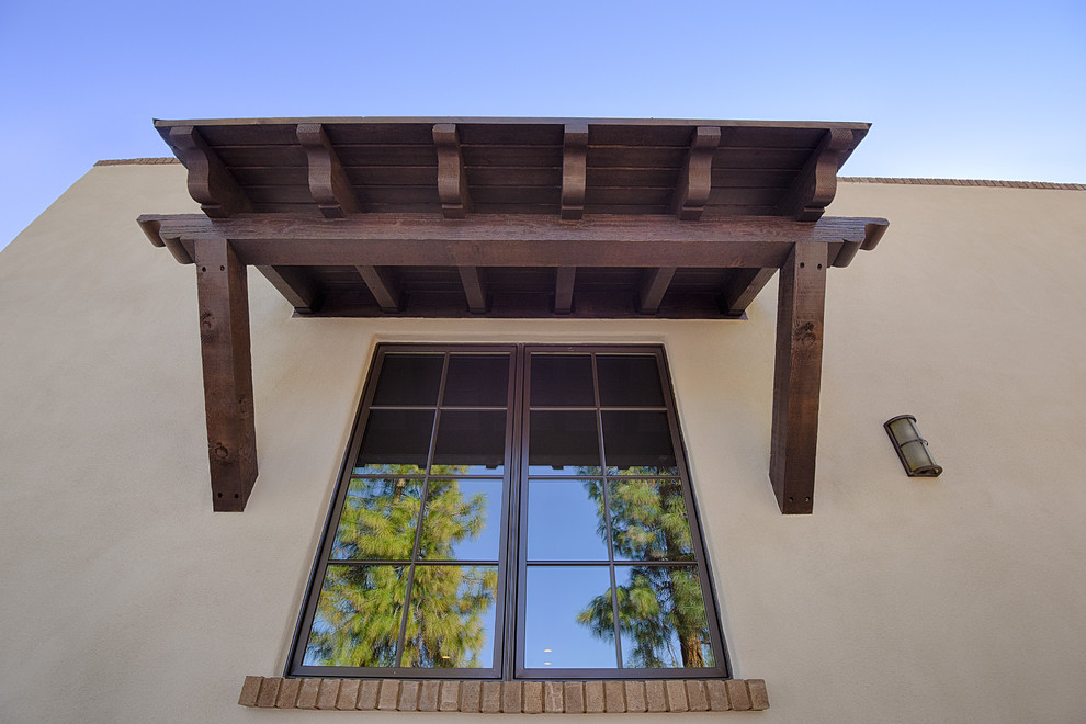 Inspiration pour une grande façade de maison beige sud-ouest américain en stuc de plain-pied avec un toit à deux pans et un toit en tuile.