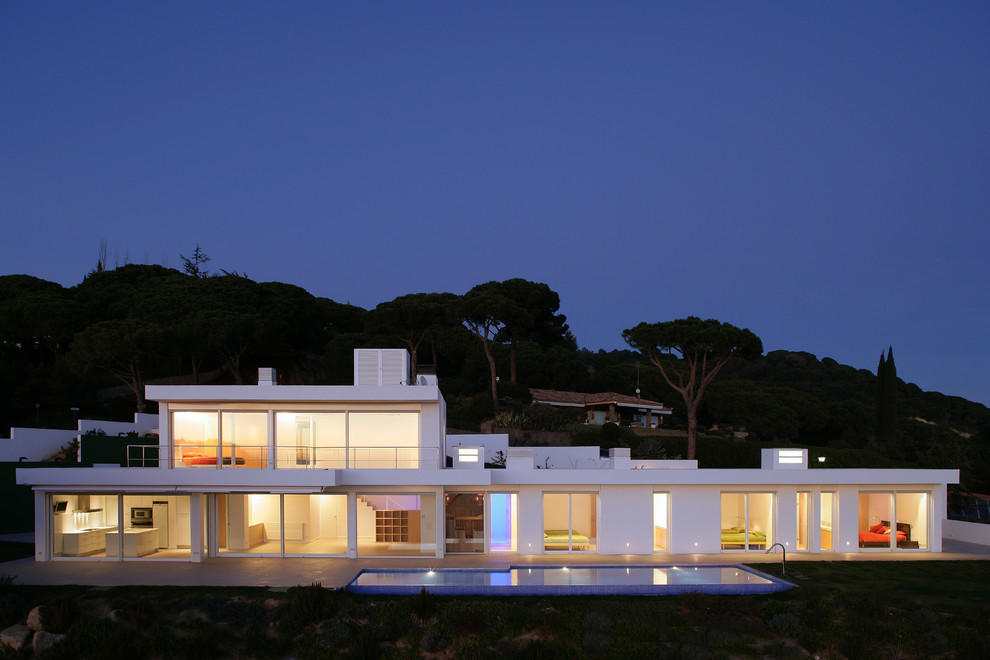 Cette photo montre une grande façade de maison blanche moderne en stuc à un étage avec un toit plat.
