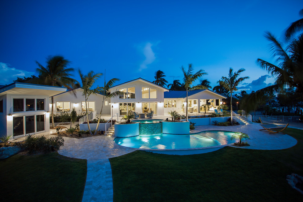 Photo of a large and white world-inspired two floor detached house in Miami with a half-hip roof and a metal roof.