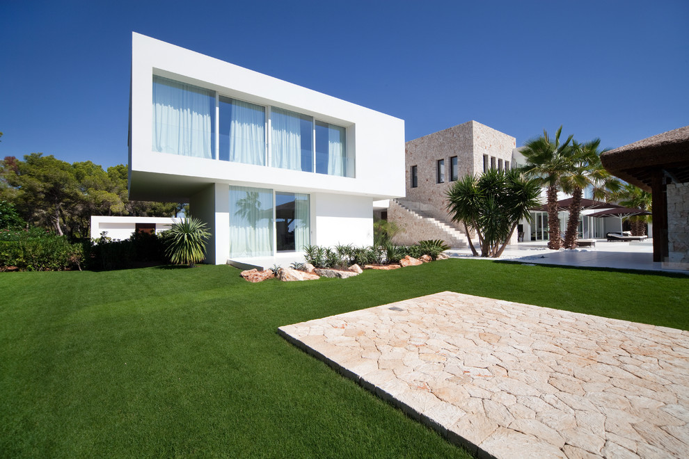 Diseño de fachada blanca tropical extra grande a niveles con revestimientos combinados y tejado plano