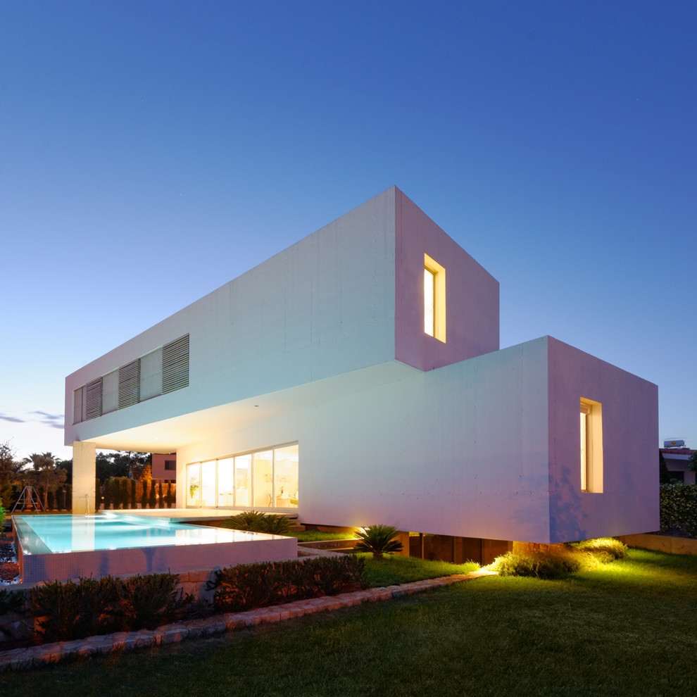 На фото: большой, двухэтажный, белый дом в современном стиле с облицовкой из цементной штукатурки и плоской крышей