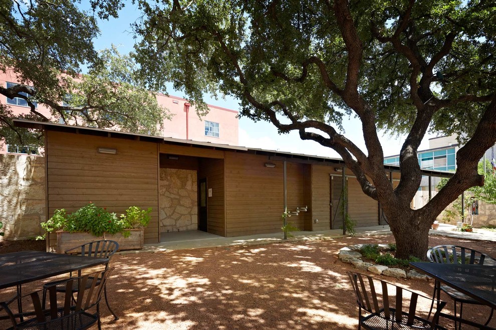 Brown and medium sized rustic bungalow house exterior in Austin with wood cladding and a lean-to roof.