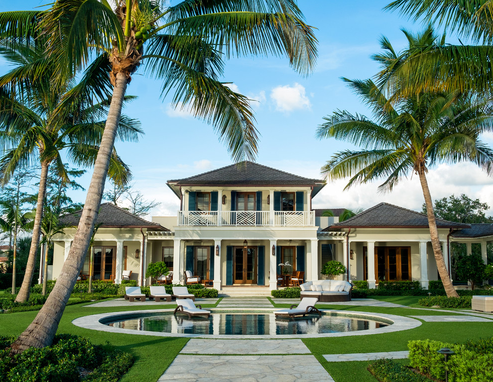 Bild på ett mycket stort tropiskt beige hus, med två våningar och stuckatur