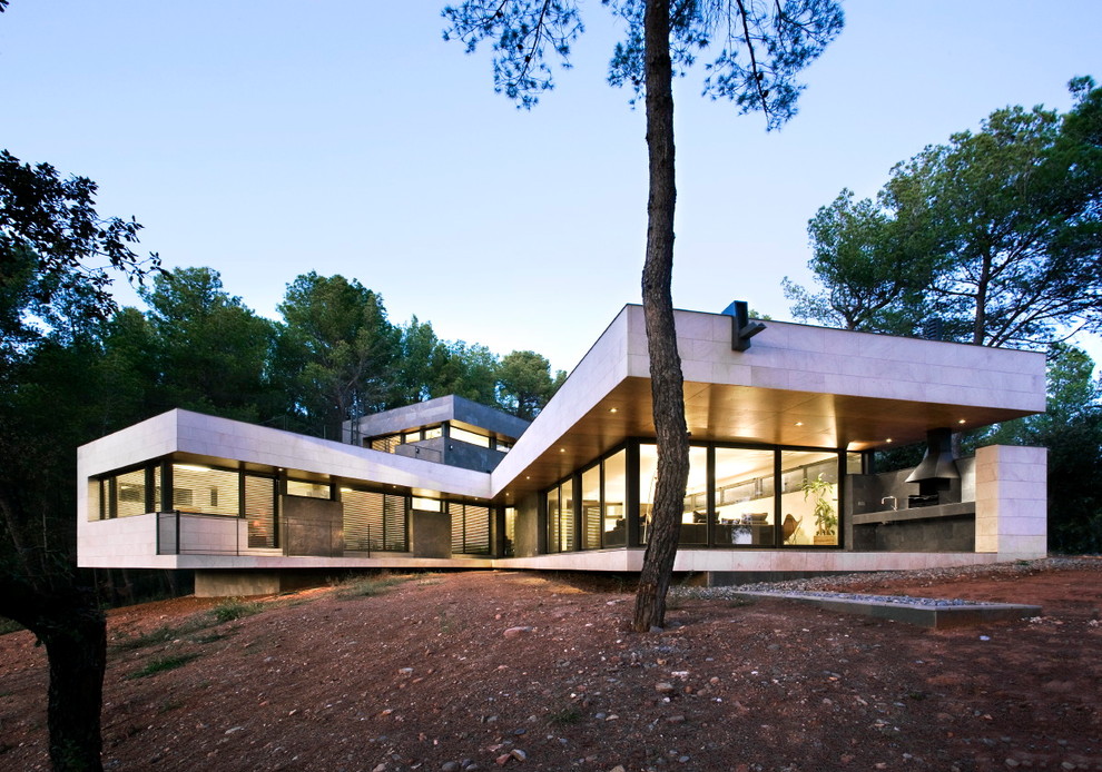 На фото: огромный, серый дом в современном стиле с разными уровнями, облицовкой из камня и плоской крышей