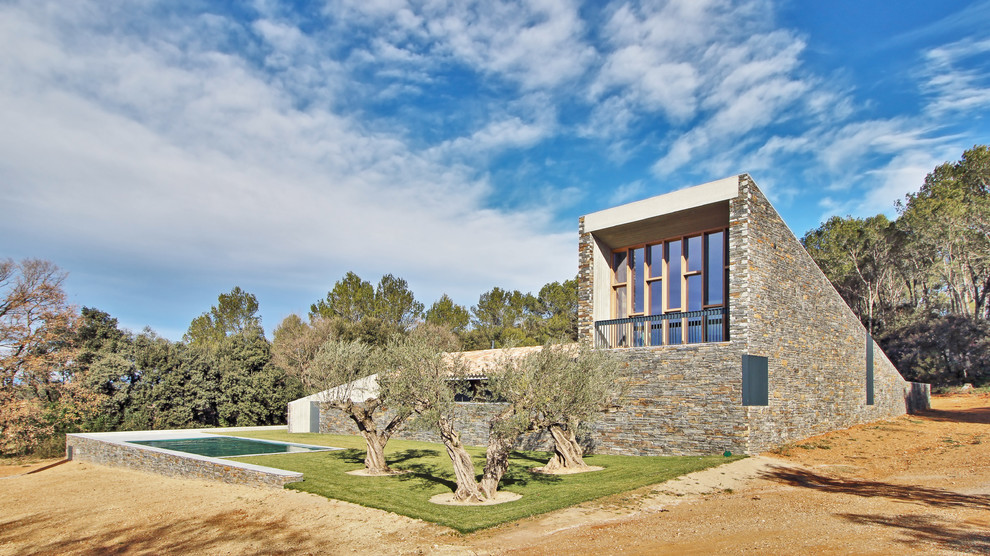 На фото: большой, двухэтажный, коричневый дом в современном стиле с облицовкой из камня и односкатной крышей