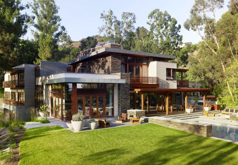 This is an example of a large and brown contemporary split-level house exterior in Other with mixed cladding and a flat roof.