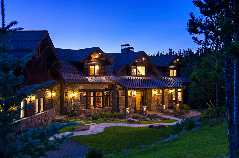 Large and brown rustic two floor house exterior in Other with stone cladding and a pitched roof.