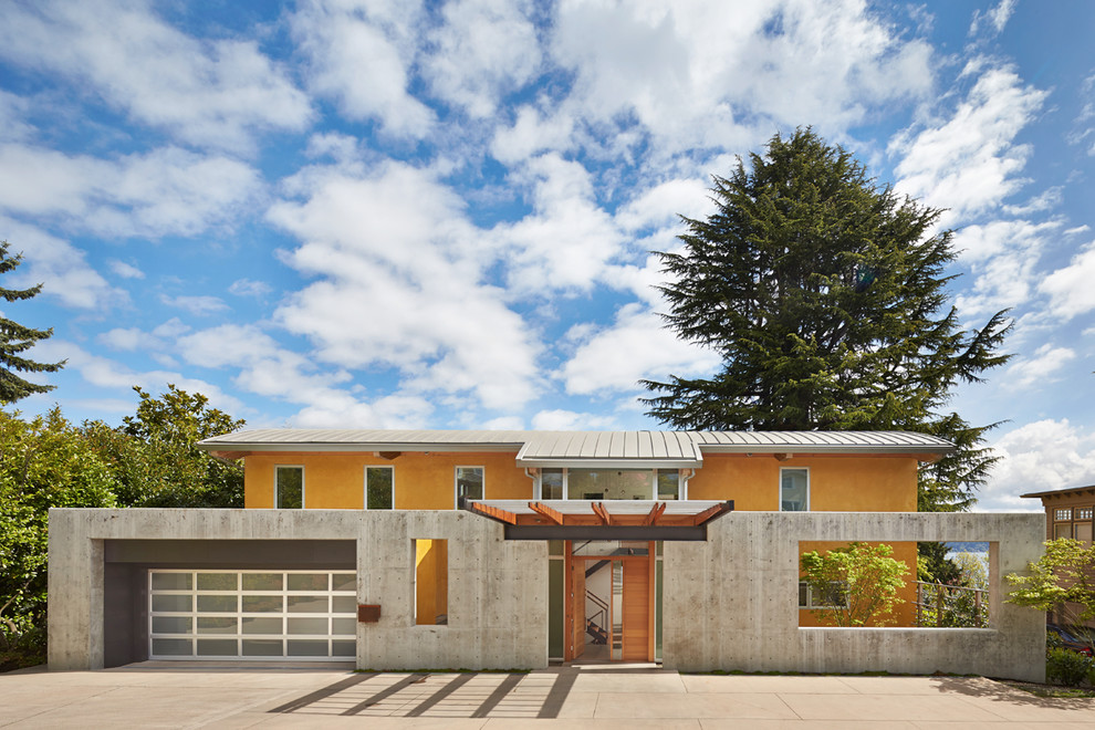 Zweistöckiges, Mittelgroßes Modernes Haus mit gelber Fassadenfarbe und Betonfassade in Seattle
