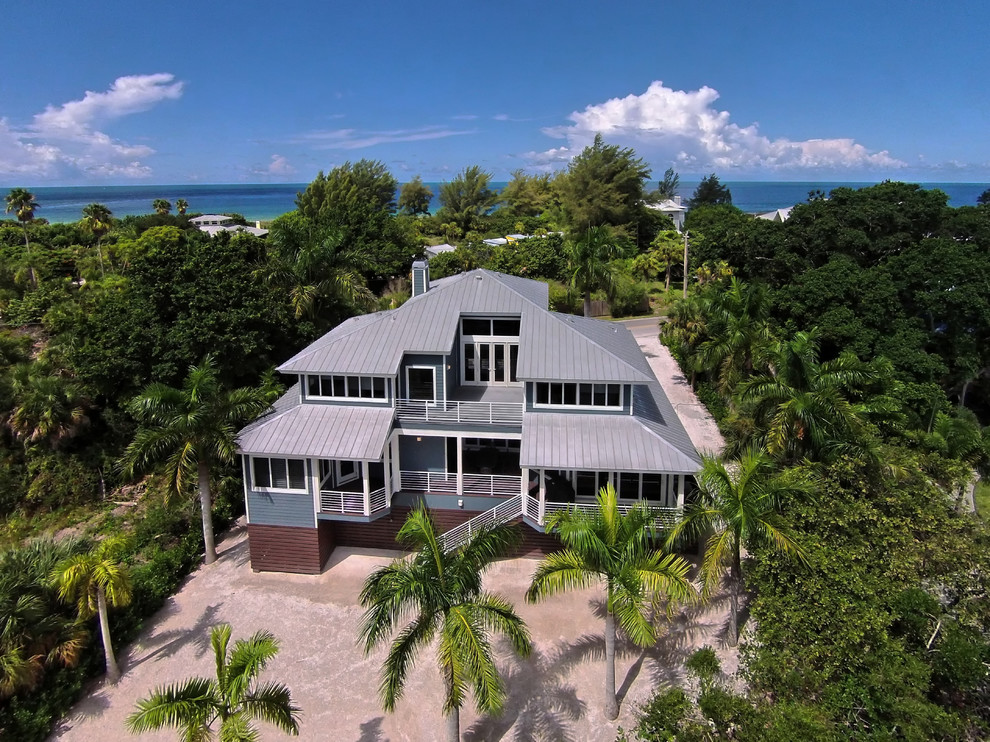 Example of a large beach style blue two-story vinyl house exterior design in Tampa with a hip roof and a metal roof