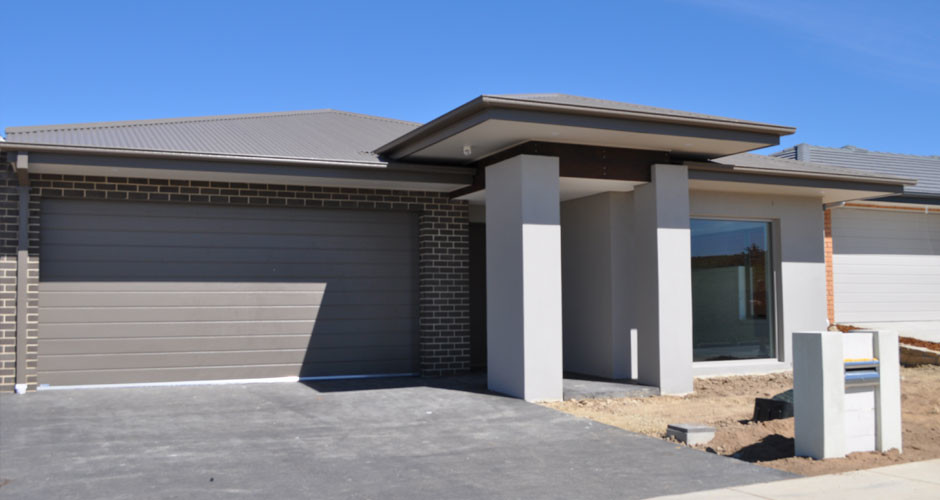 Example of a mid-sized trendy gray one-story brick exterior home design in Canberra - Queanbeyan with a hip roof