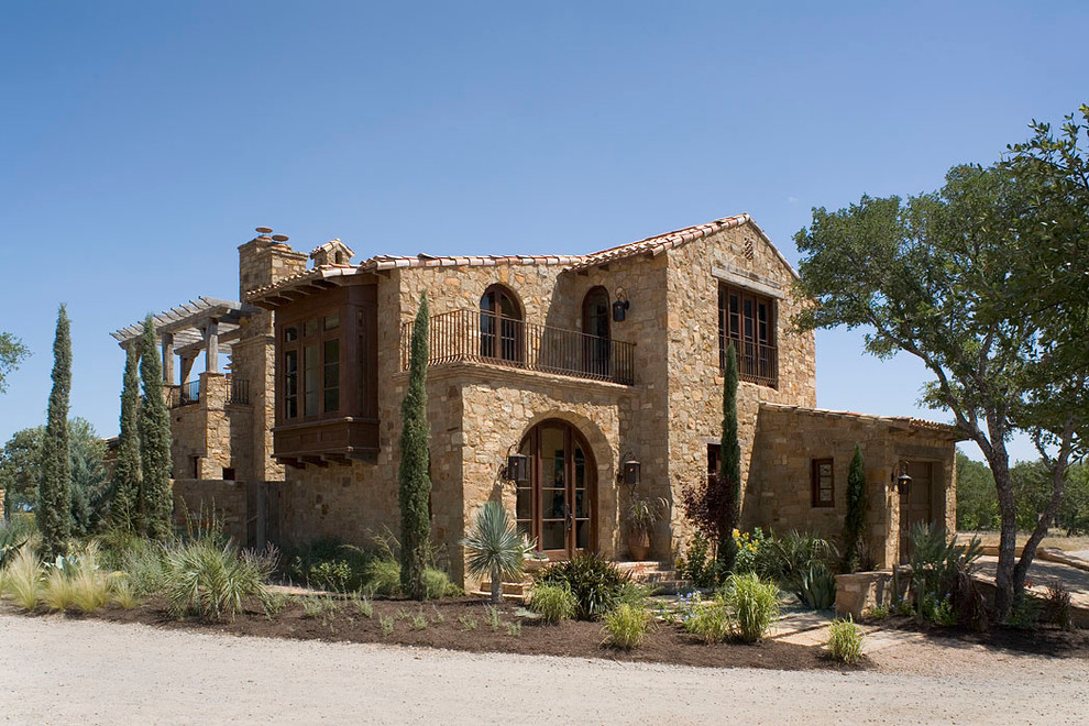 Inspiration for a mediterranean two floor house exterior in Austin with stone cladding.