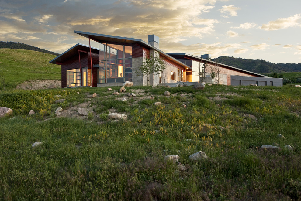 Réalisation d'une grande façade de maison rouge design à un étage avec un revêtement mixte et un toit en appentis.