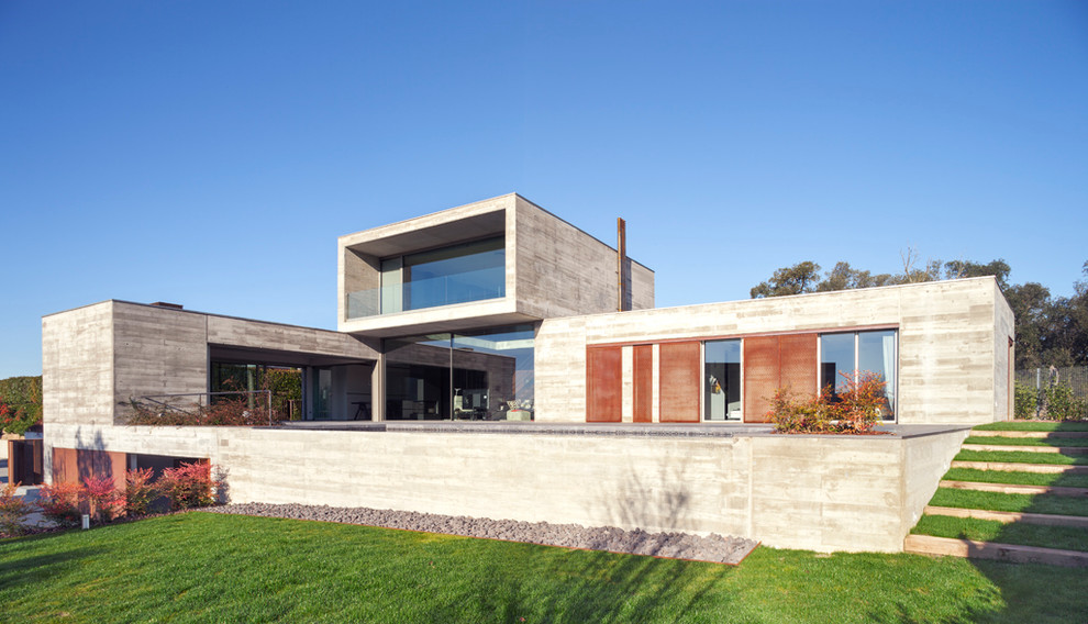 Réalisation d'une très grande façade de maison grise design en béton à deux étages et plus avec un toit plat.