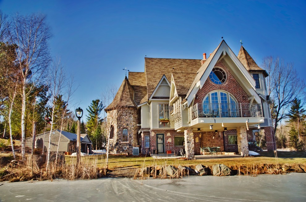 Foto della villa grande multicolore rustica a tre piani con rivestimenti misti, tetto a capanna e copertura a scandole