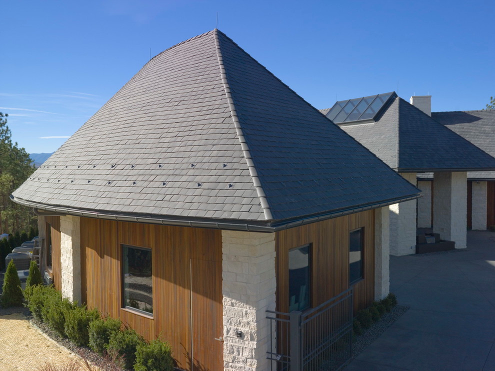 Diseño de fachada de casa beige actual grande de tres plantas con revestimiento de piedra, tejado a cuatro aguas y tejado de teja de madera