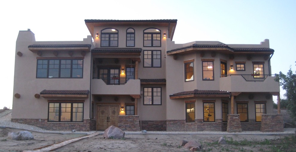 Aménagement d'une grande façade de maison beige sud-ouest américain en stuc à deux étages et plus avec un toit plat.