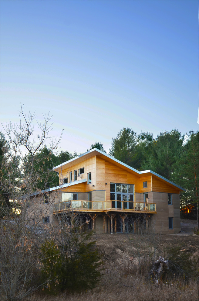 На фото: двухэтажный, бежевый дом среднего размера в стиле модернизм с облицовкой из самана и односкатной крышей с