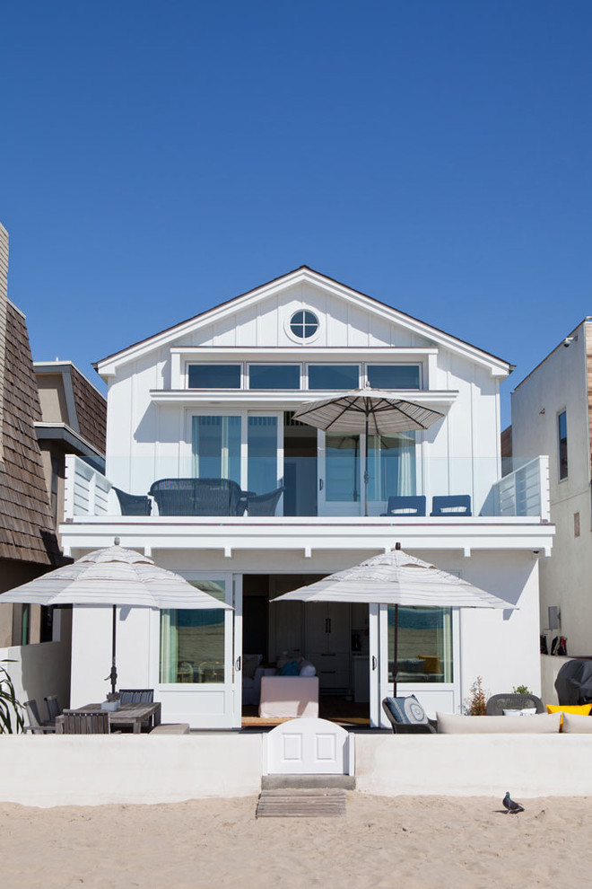 Cette image montre une petite façade de maison blanche marine en bois à un étage avec un toit à deux pans.
