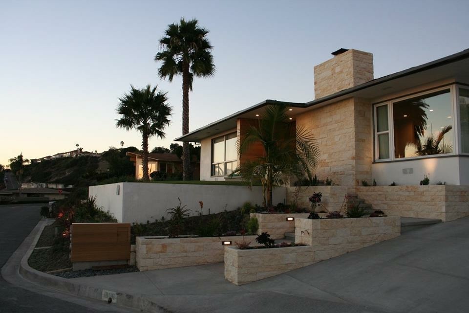 Cette photo montre une grande façade de maison beige rétro en pierre de plain-pied avec un toit plat.