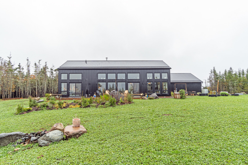 Immagine della villa nera eclettica di medie dimensioni con rivestimento in metallo, tetto nero e pannelli e listelle di legno