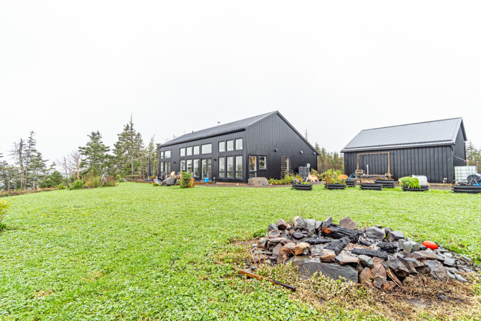 Cette photo montre une façade de maison métallique et noire éclectique en planches et couvre-joints de taille moyenne avec un toit noir.