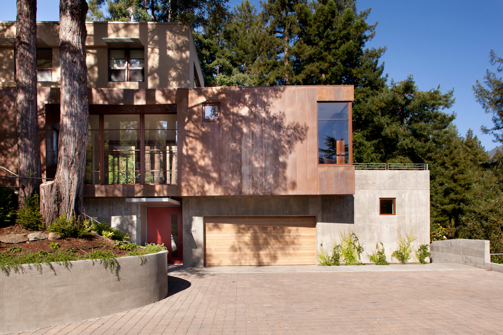 Cette photo montre une grande façade de maison marron moderne en béton à un étage avec un toit plat.