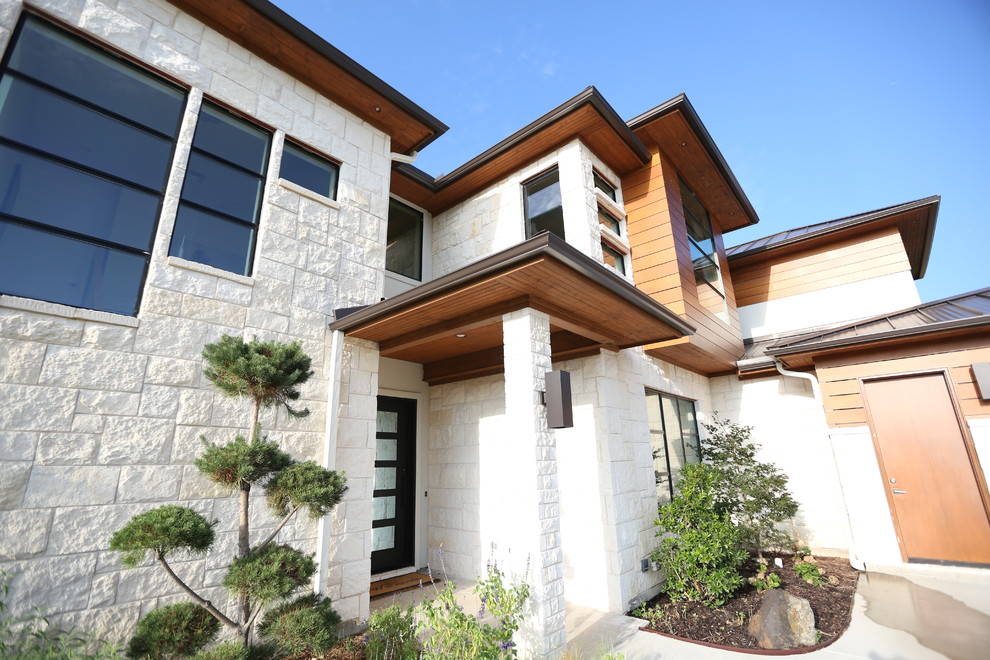 Diseño de fachada de casa blanca actual de tamaño medio de dos plantas con revestimiento de piedra, tejado a cuatro aguas y tejado de metal