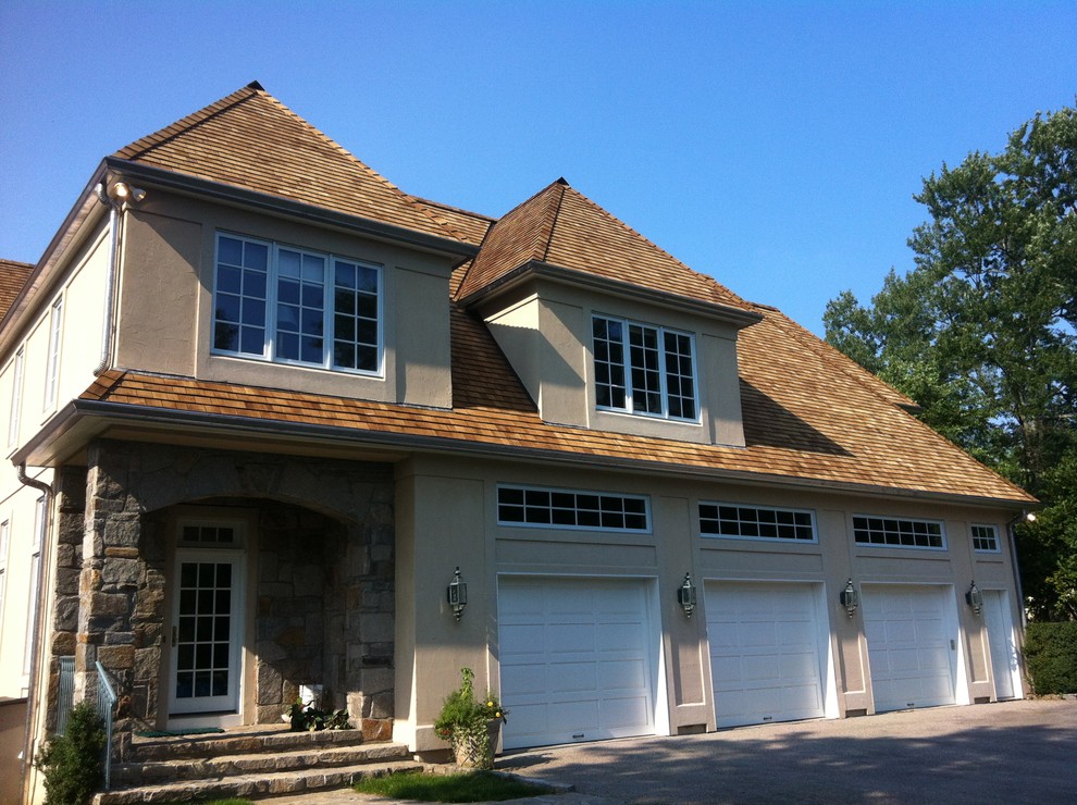 Large elegant beige two-story stucco house exterior photo in New York with a hip roof and a shingle roof