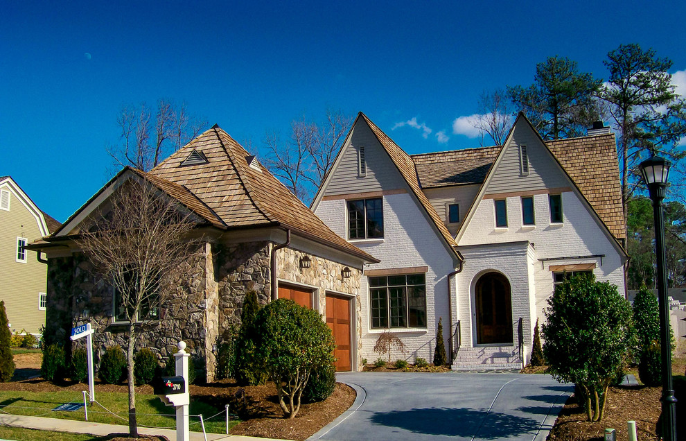 Example of a large mid-century modern white two-story brick exterior home design in Charlotte with a clipped gable roof